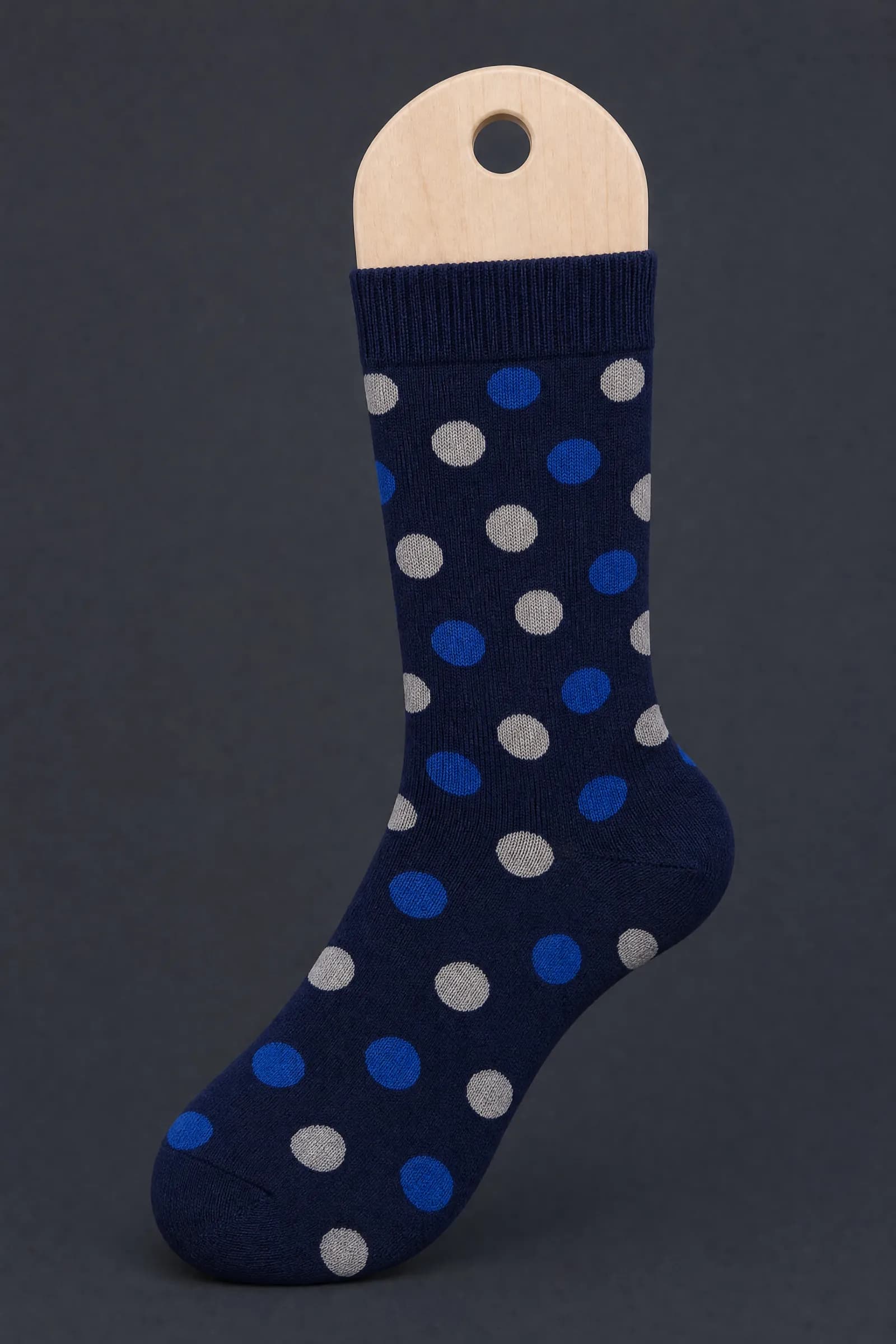 The Dot Scatter pattern on a sock stretched over a sock form, showing how the drawing curves and compresses