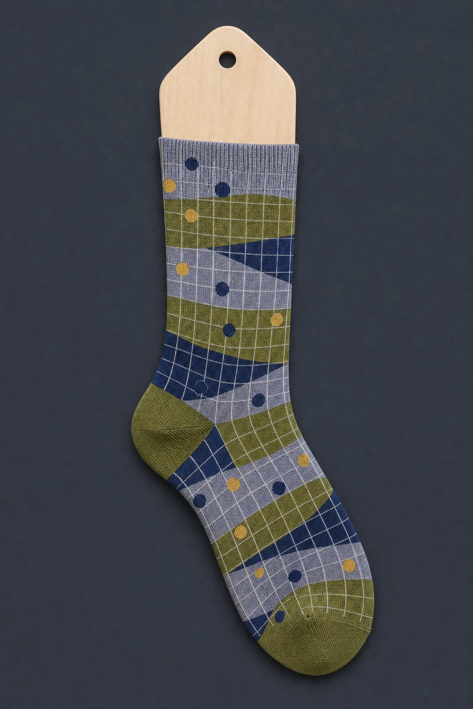 The Geometric Premium pattern on a sock stretched over a sock form, showing how the drawing curves and compresses
