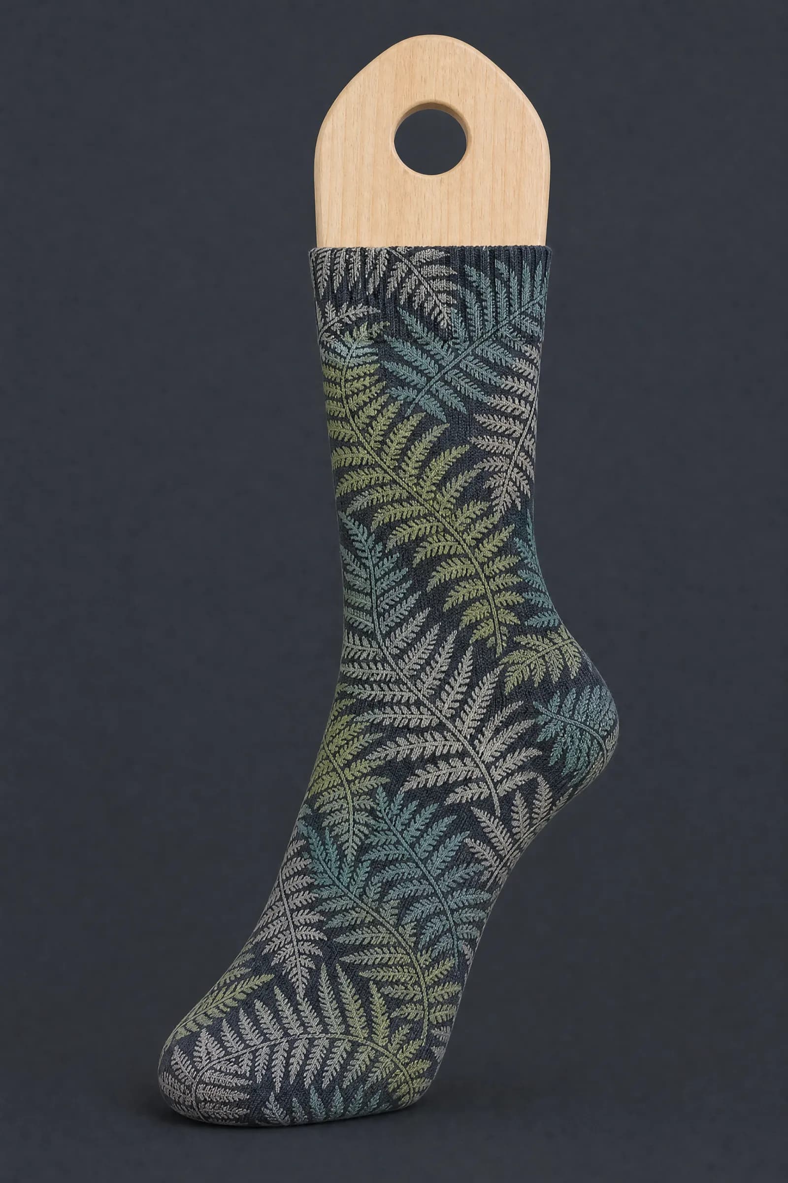 The Fern Dense pattern on a sock stretched over a sock form, showing how the drawing curves and compresses