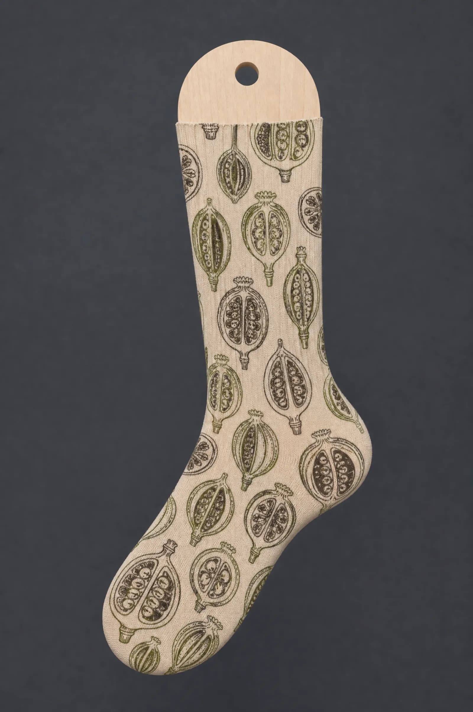 The Seed Pod pattern on a sock stretched over a sock form, showing how the drawing curves and compresses