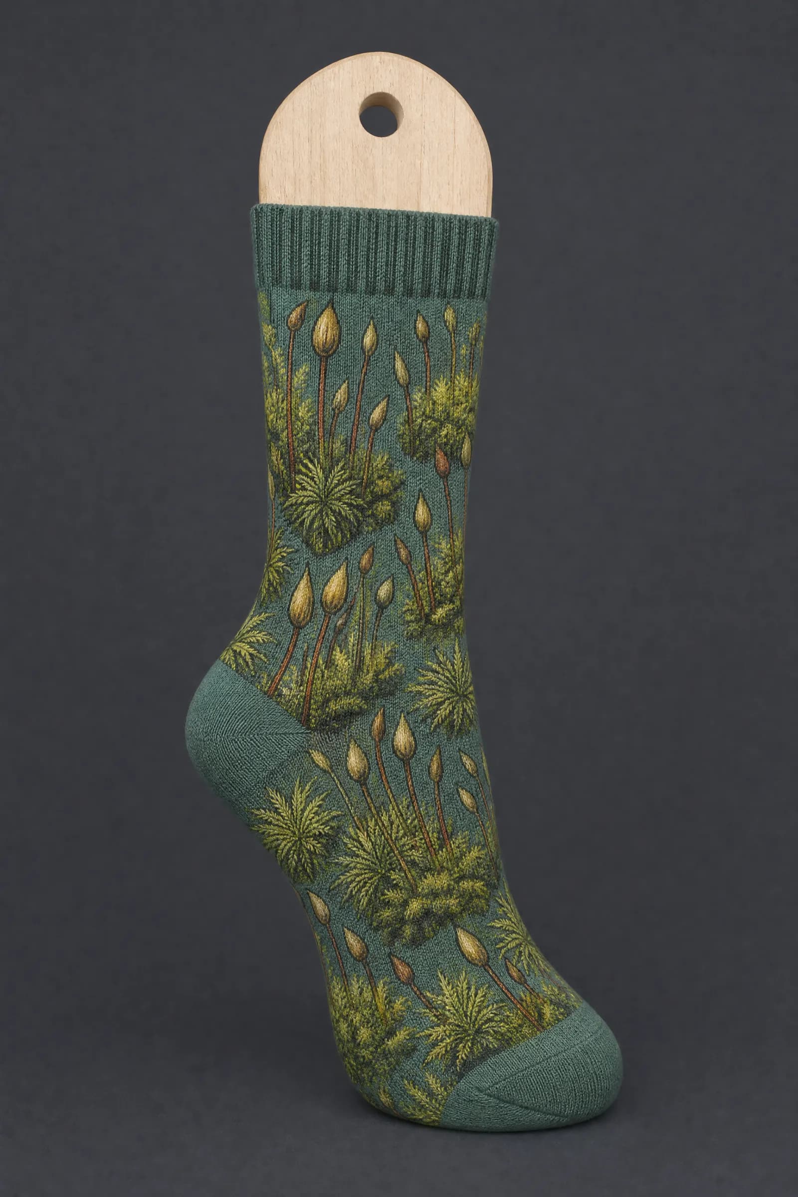 The Moss Macro pattern on a sock stretched over a sock form, showing how the drawing curves and compresses