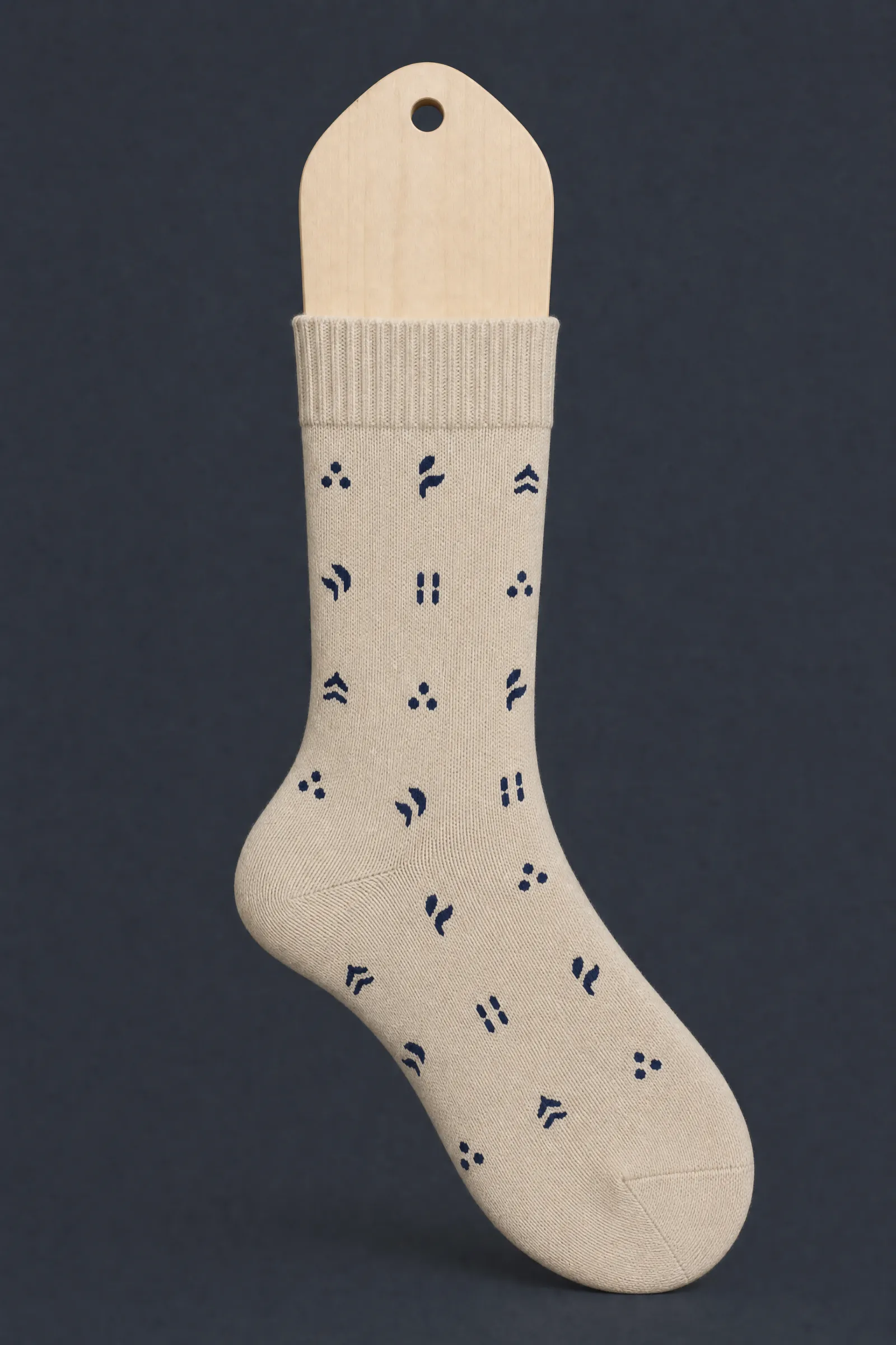 The Mark Small pattern on a sock stretched over a sock form, showing how the drawing curves and compresses
