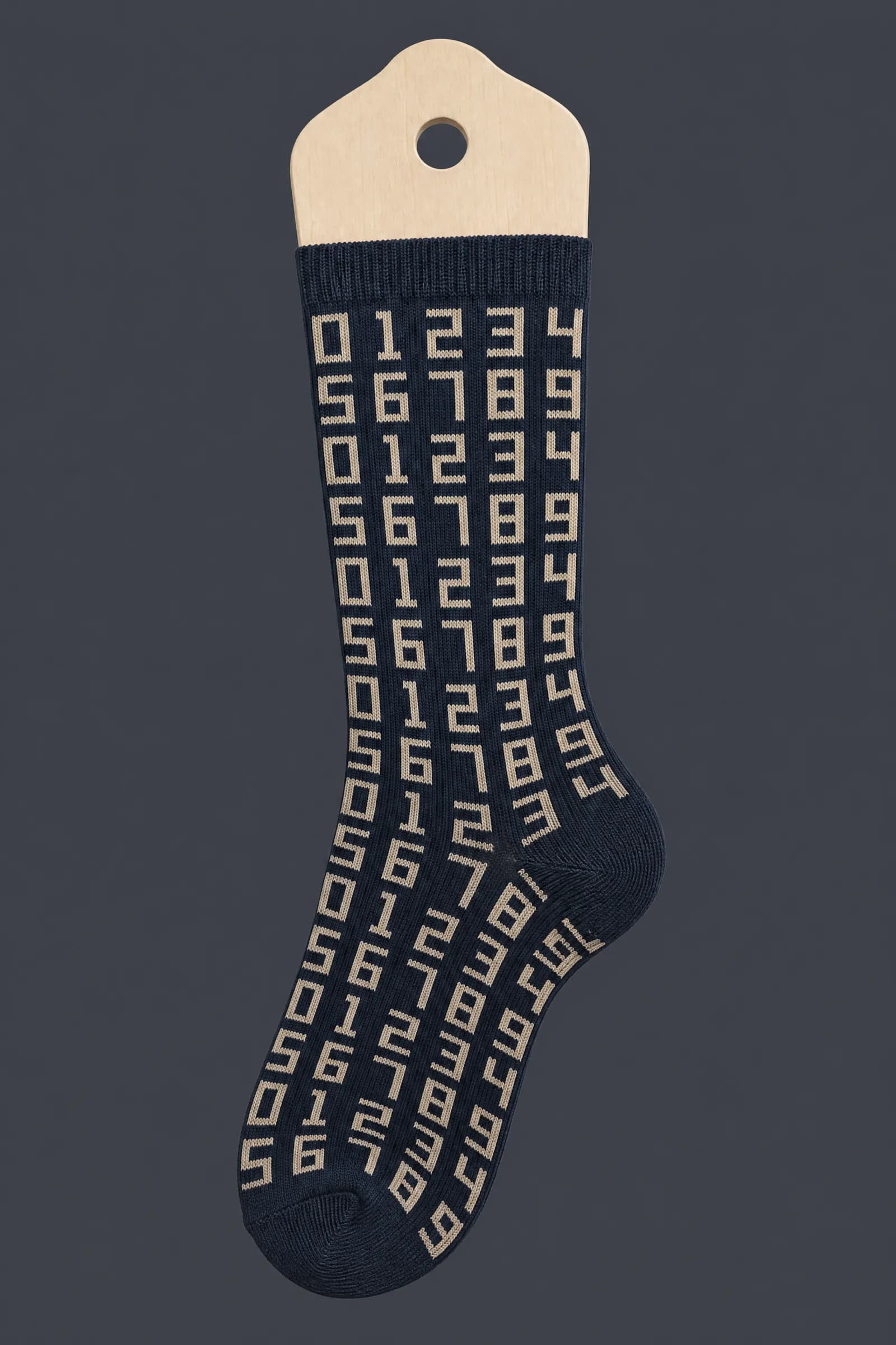 The Numeral Grid pattern on a sock stretched over a sock form, showing how the drawing curves and compresses