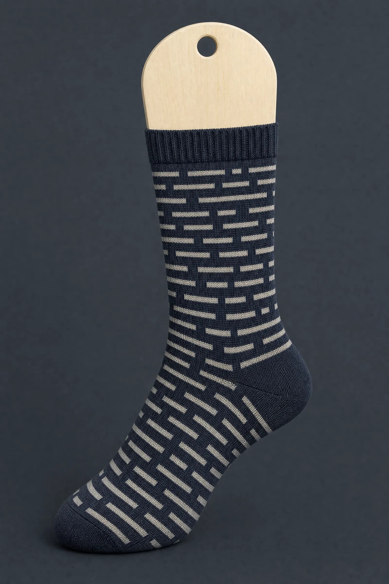 The Dash Code pattern on a sock stretched over a sock form, showing how the drawing curves and compresses
