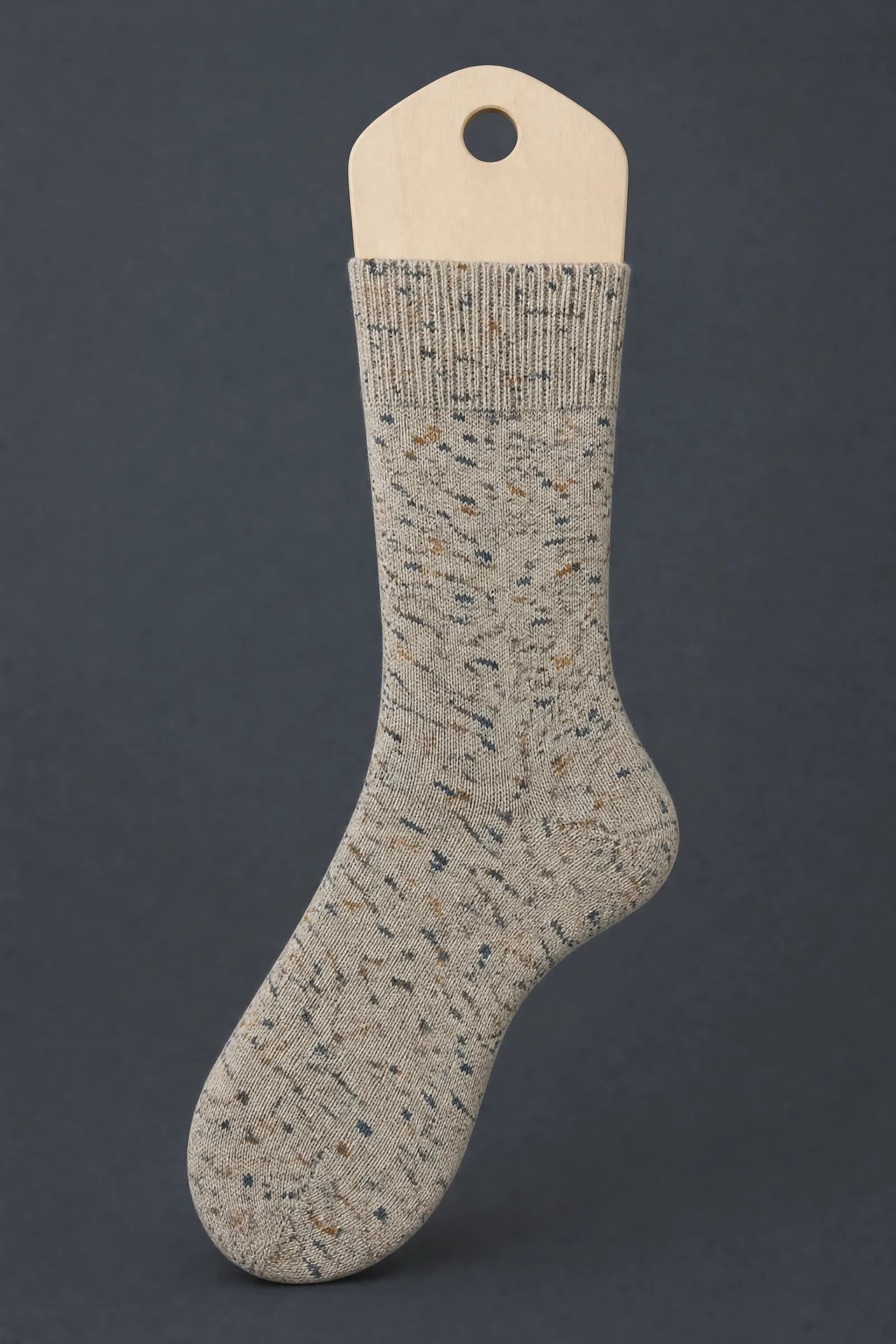 The Faux Tweed pattern on a sock stretched over a sock form, showing how the drawing curves and compresses